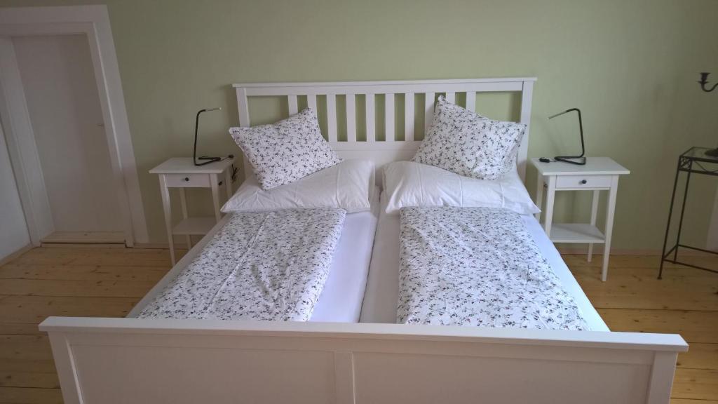 德意志克罗伊茨Rosenappartement-Deutschkreutz的一张带两个枕头和两张桌子的白色床