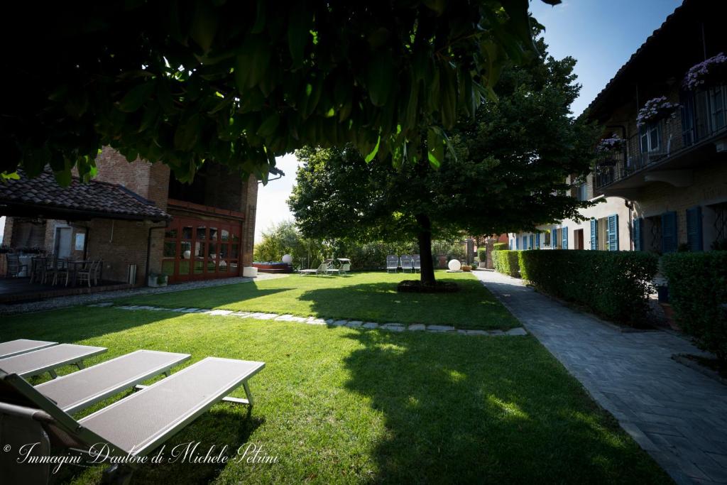 瓜热讷La Madernassa Resort - Casalora Dimora Storica di Charme的坐在树旁的草上的一个白色长凳