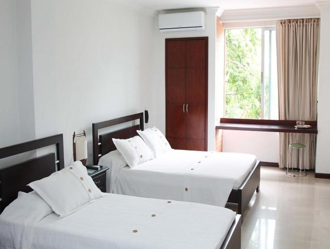 卡利Pampalinda Hotel的酒店客房设有两张床和窗户。
