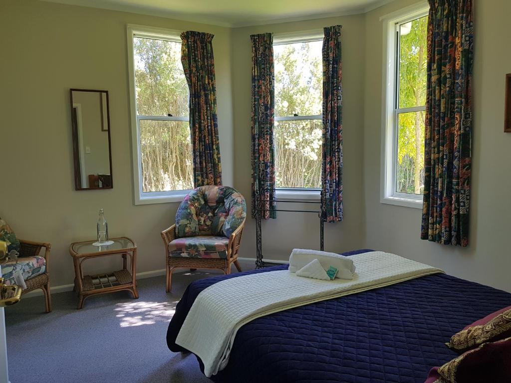 BullsLancewood Lodge的一间卧室配有一张床、一把椅子和窗户。