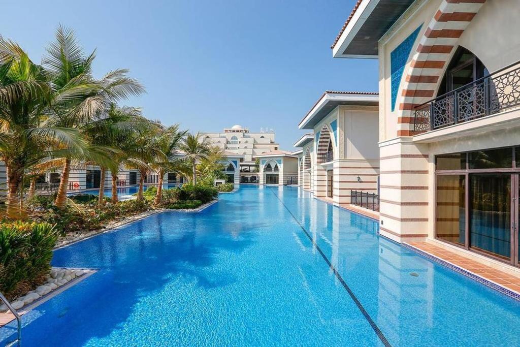 迪拜Zabeel Saray Royal Residences Lagoon Villa的棕榈树别墅内的游泳池