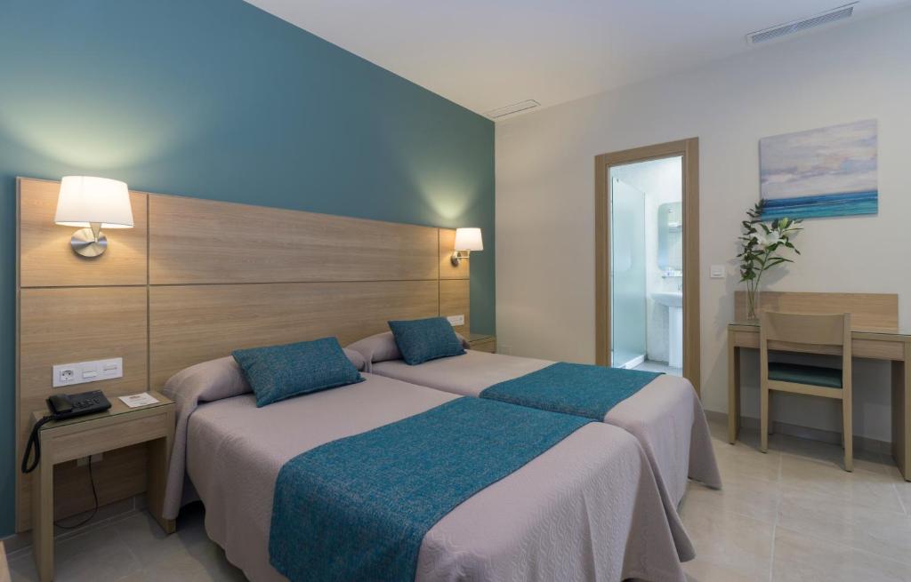 马拉加苏马拉加酒店的一间卧室配有两张床和一张桌子及一张桌子。