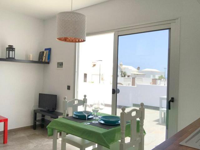 查德尔帕罗奥Sunny Studio Lanzarote的一间设有绿色桌椅和窗户的用餐室