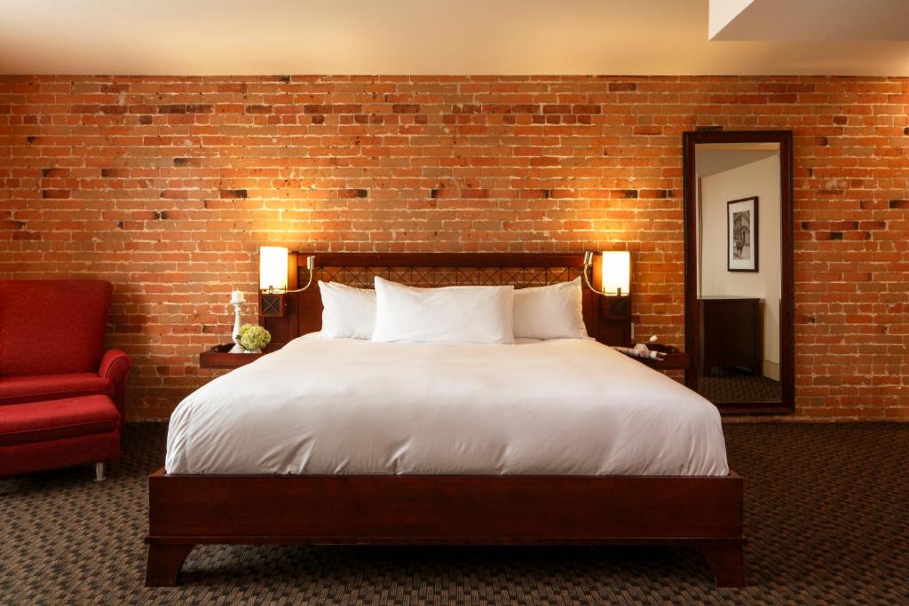 蒙特利尔内利冈酒店的一间卧室设有一张大床和砖墙
