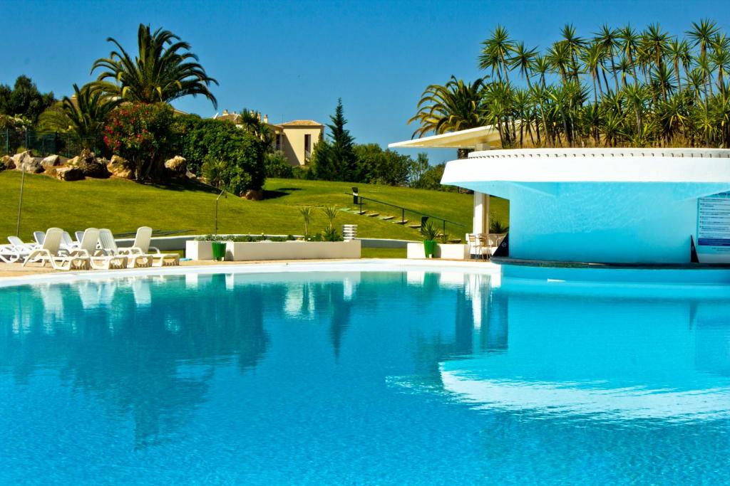 阿尔沃尔Vila Marachique Torralvor的一个带白色椅子和棕榈树的蓝色游泳池