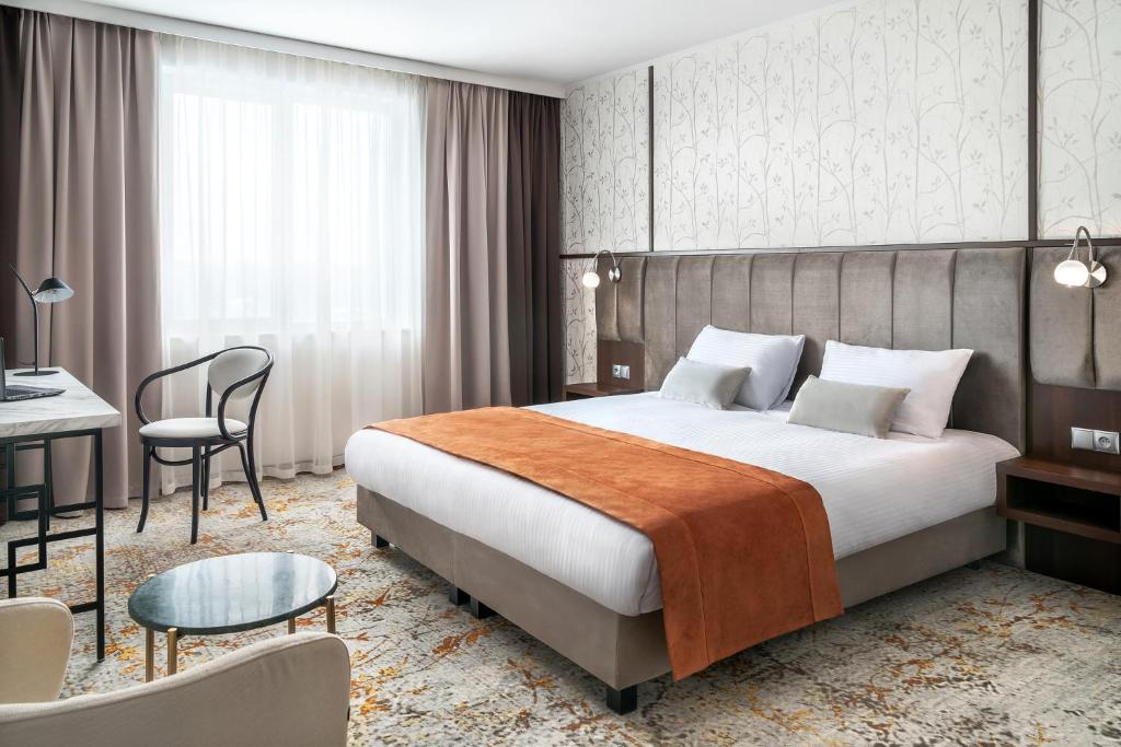 克拉科夫Metropolo by Golden Tulip Krakow的配有一张床和一张书桌的酒店客房