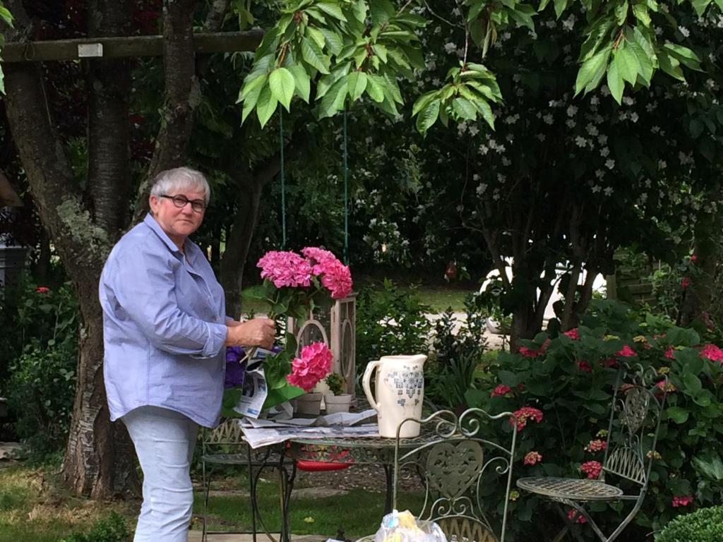 Vaux-sur-Aure科特康帕涅酒店的一位年纪较大的妇女站在一张花桌子旁边