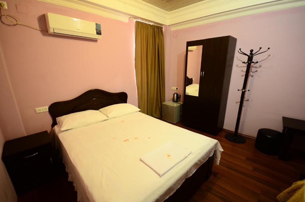 巴统Hotel Peria的一间卧室配有一张带白色床单和镜子的床