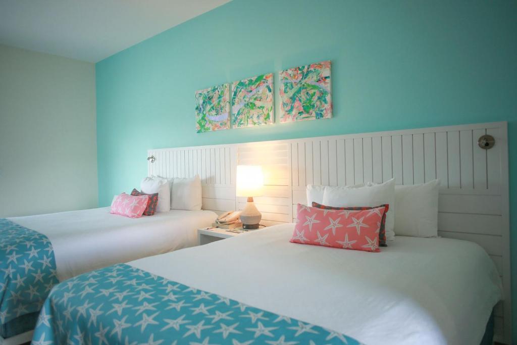 自由港市派力肯湾酒店的两张位于酒店客房的床,拥有蓝色的墙壁