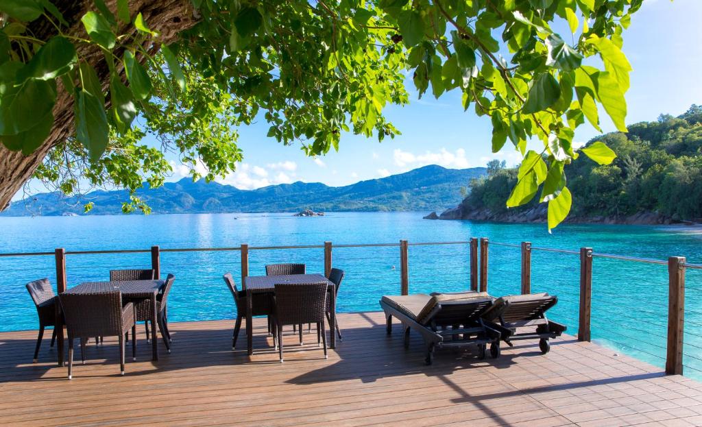 马埃岛贝拉扎尔区Anse Soleil Beachcomber Hotel and Self Catering的湖景甲板配有桌椅