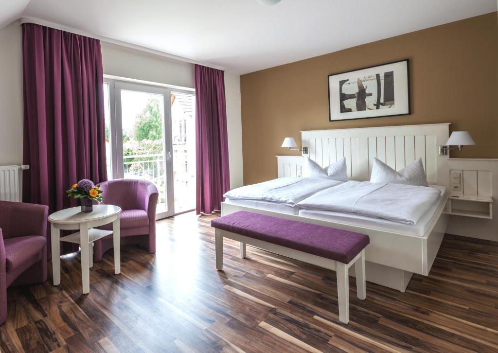 塞巴特阿尔贝克德利亚维尔旅馆的卧室配有一张白色大床和紫色椅子