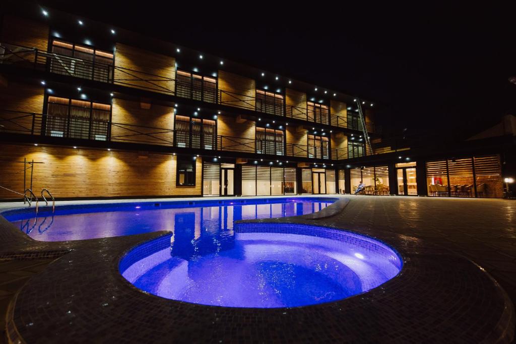 塔拉兹Barhat Resort的一座大型建筑,前面有一个蓝色的游泳池