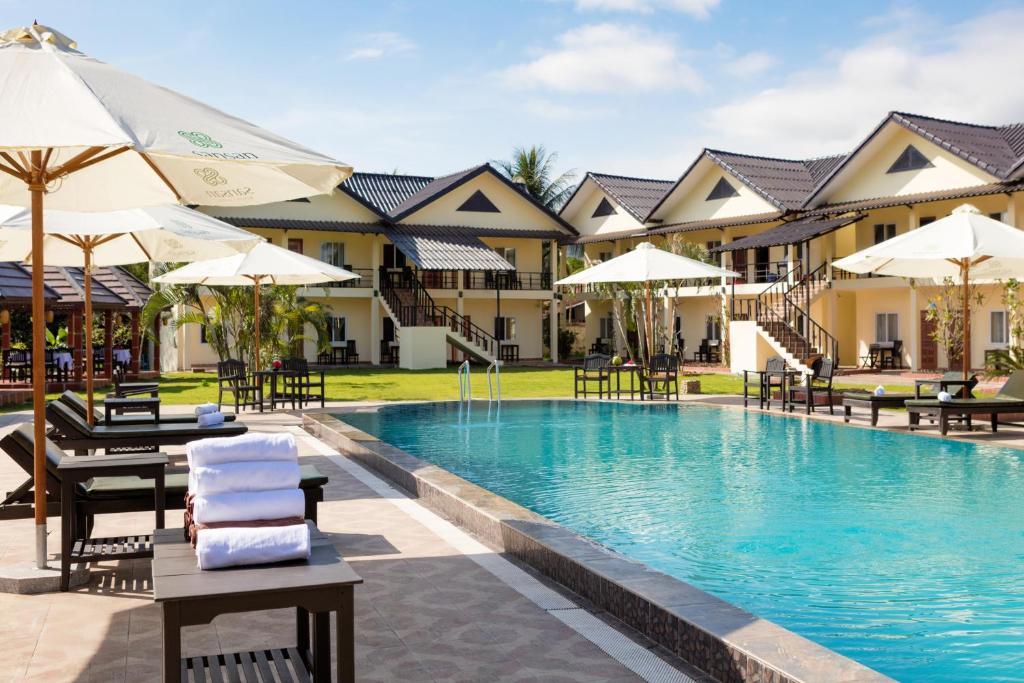 万荣Sansan Resort的一个带躺椅和遮阳伞的度假游泳池