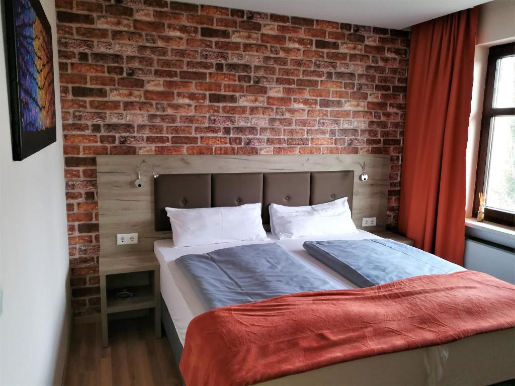 莱希河畔兰茨贝格Landhotel Römerkessel的砖墙房间的一个床位