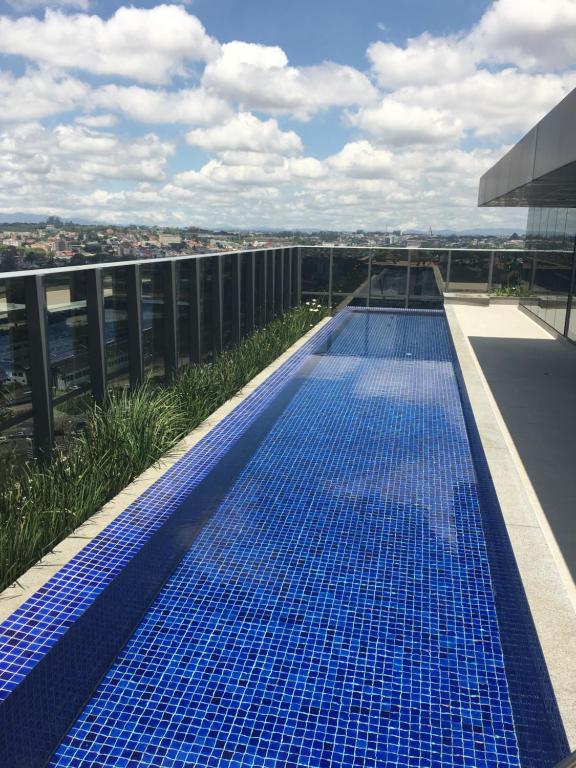 库里提巴Estudio moderno com linda vista para a Serra的建筑物屋顶上的蓝色游泳池