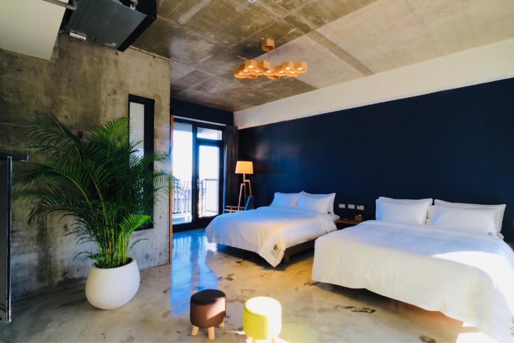 Dahan七星潭泥作轻旅民宿的一间卧室设有两张床和盆栽植物