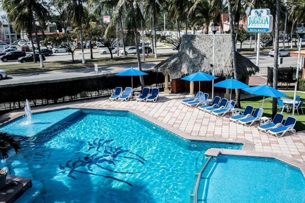 韦拉克鲁斯雅拉瓜酒店的一个带椅子和遮阳伞的大型游泳池