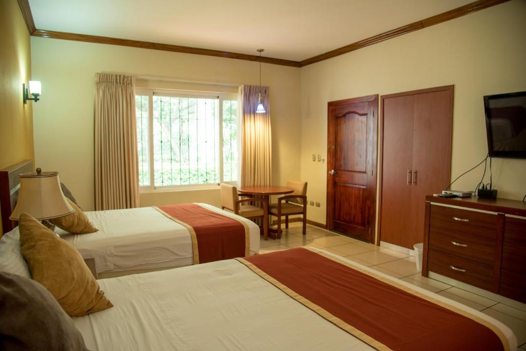 San LuisPato Canales Hotel & Resort的酒店客房设有两张床和一张桌子。