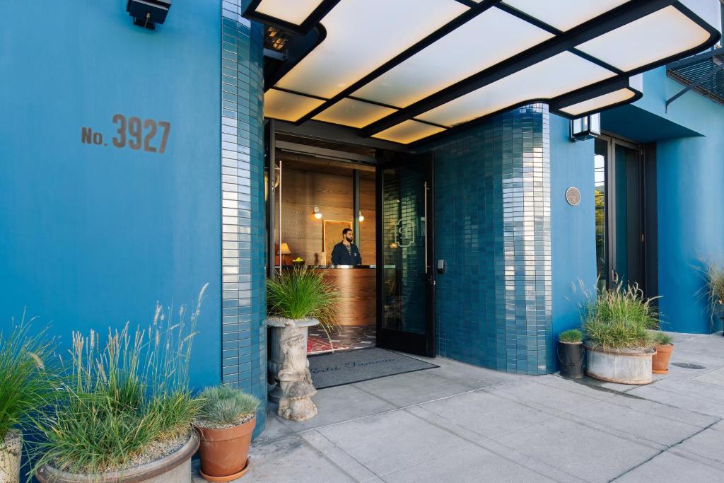 洛杉矶Palihotel Culver City的一座蓝色的建筑,一个人站在门口