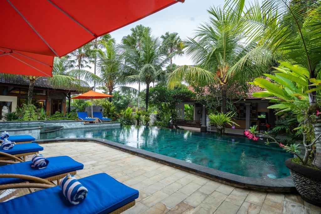海神庙海神庙纳特雅酒店的度假村的游泳池,设有蓝色的椅子和棕榈树