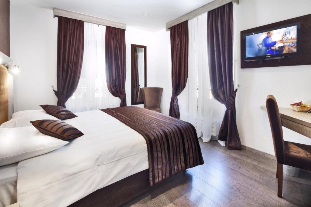 日内瓦Hotel Strasbourg的卧室配有一张床,墙上配有电视。