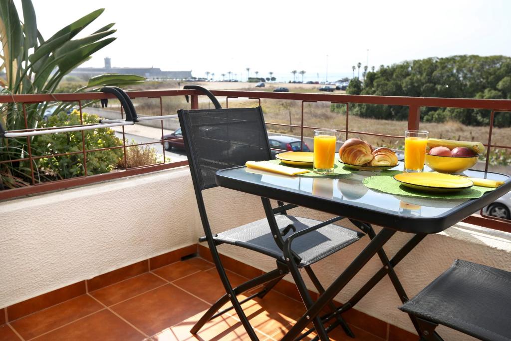 卡尔卡维洛斯Like-home Sea View Apt的阳台上的桌子上摆放着食物和橙汁