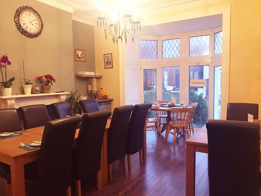 朴次茅斯Esk Vale Guest House的一间带桌椅和时钟的用餐室
