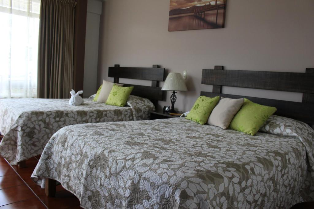 福尔图纳Hotel Arenal By Regina的一间卧室配有两张带绿色枕头的床