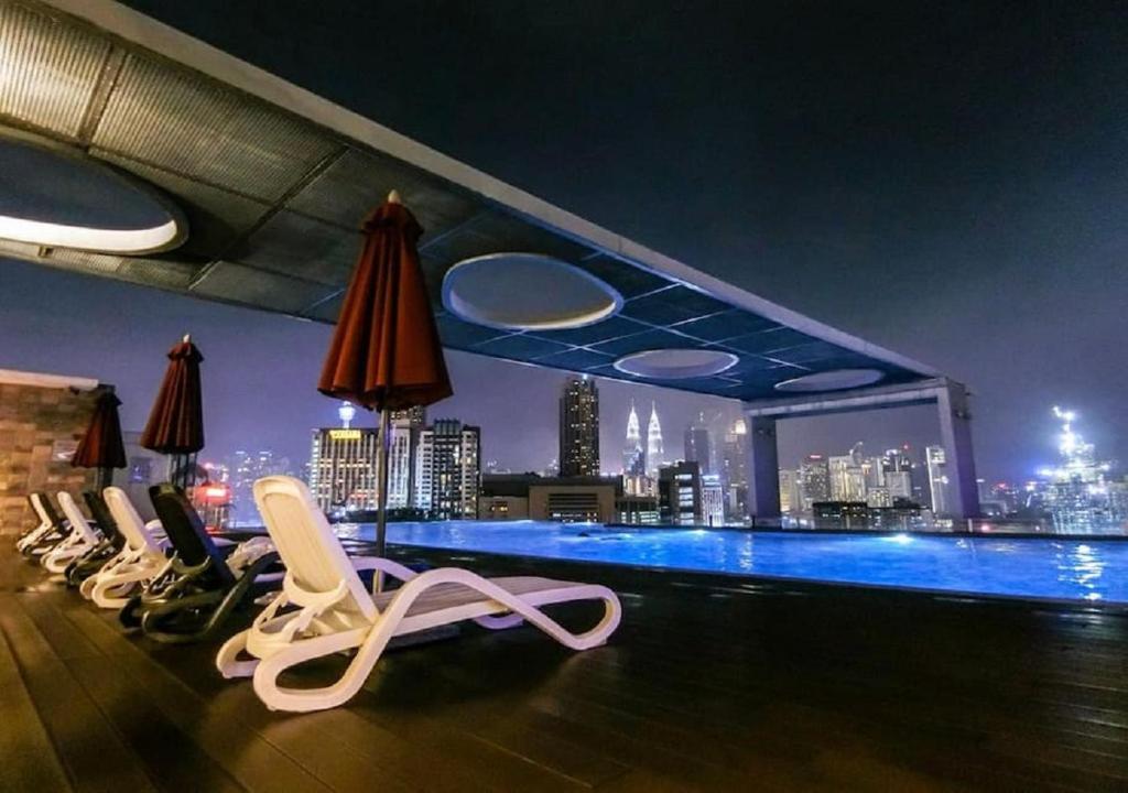 吉隆坡Maxhome @ D'Majestic Place, KL City Centre的屋顶酒吧设有椅子,享有城市美景