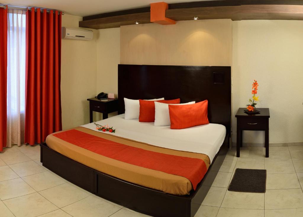 阿瓜斯卡连特斯伊丽莎白体育城酒店的一间卧室配有一张带橙色枕头的大床