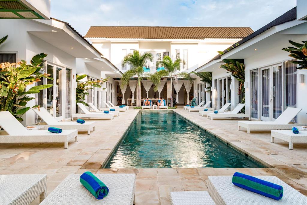 吉利特拉旺安Cocotoa Boutique Hotel & Villa的度假村中心的一个游泳池,配有白色躺椅