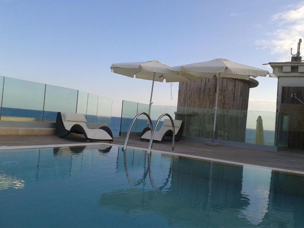 安齐奥阿普罗多酒店的一个带椅子和遮阳伞的游泳池
