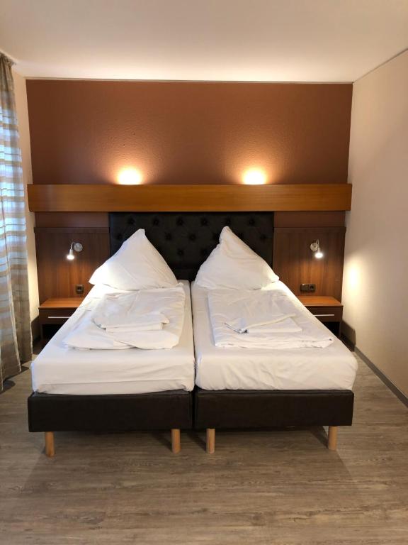 拜罗伊特波塞冬酒店的一张位于房间的床,上面有两个枕头