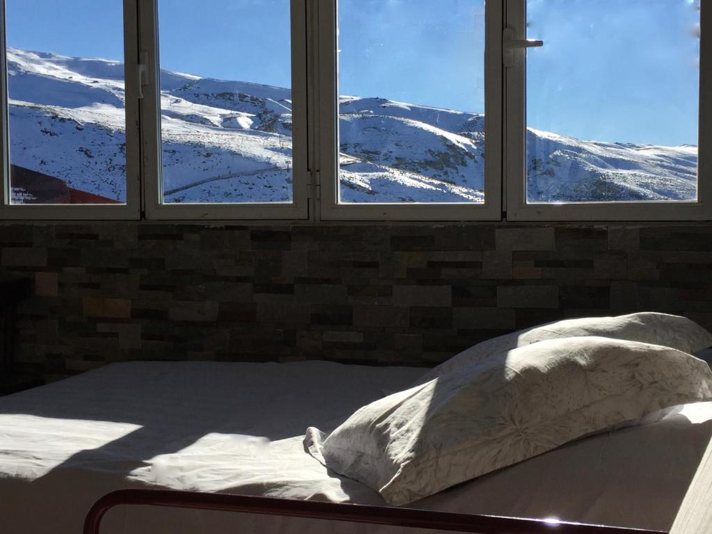塞拉内华达Sol del Sur Sierra Nevada的一张位于带三扇窗户的房间里,窗户被雪覆盖着
