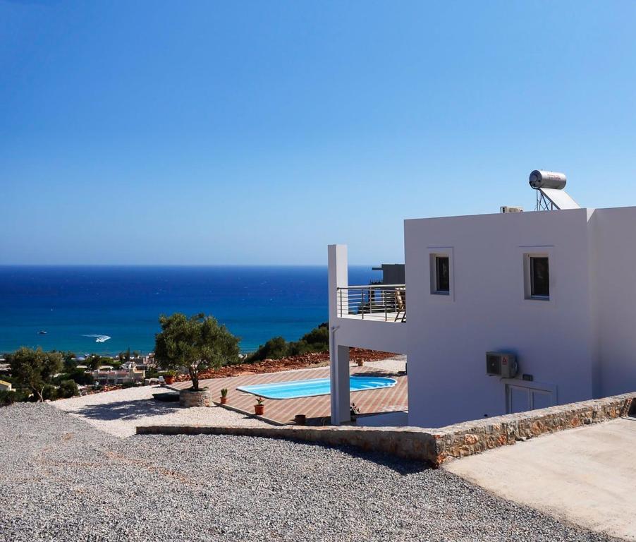斯塔里斯Villa Xenia Stalis的白色的房子,设有一个游泳池和大海