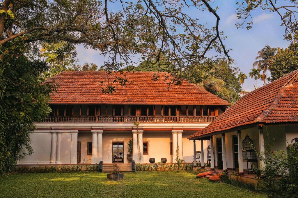 科钦Chittoor Kottaram Royal Mansion- CGH Earth的一座在院子里有红色屋顶的老房子