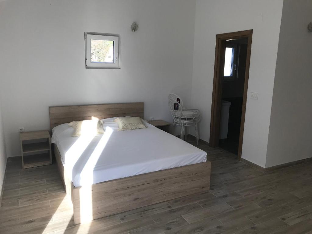 耶泽拉Apartments Sanja的一间卧室配有一张带白色床单的床和一扇窗户。