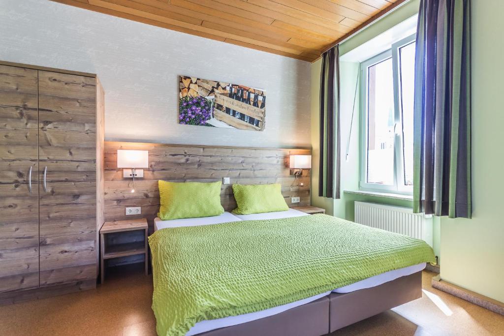 策尔廷根-拉蒂希阿尔特斯舒尔豪斯酒店的一间卧室配有一张带绿色床单的床和一扇窗户。