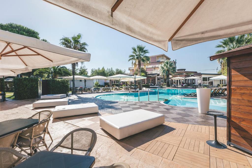 瓦斯托Hotel Acquario的一个带桌椅和遮阳伞的游泳池
