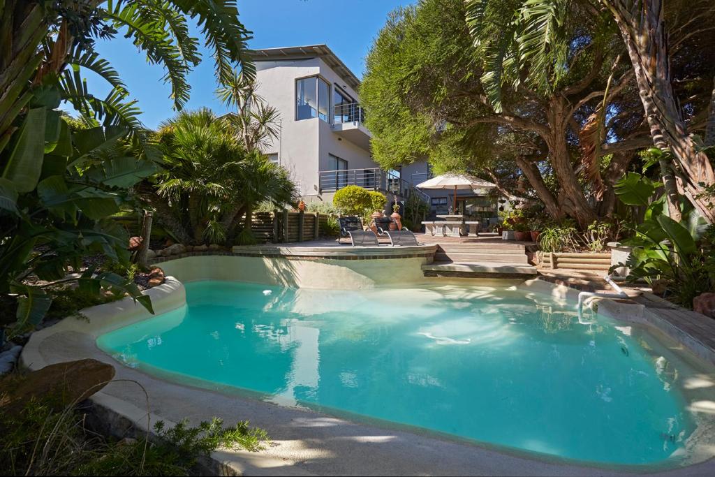 豪特湾Villa Rhulani - Luxurious modern Villa in Hout Bay的一座树木繁茂的房屋前的游泳池