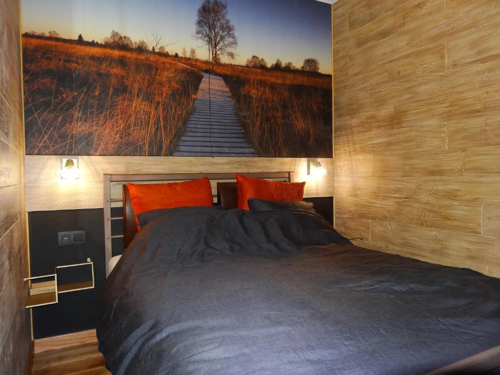 马尔梅迪La mignonne des fagnes的卧室配有一张大床,墙上挂有绘画作品