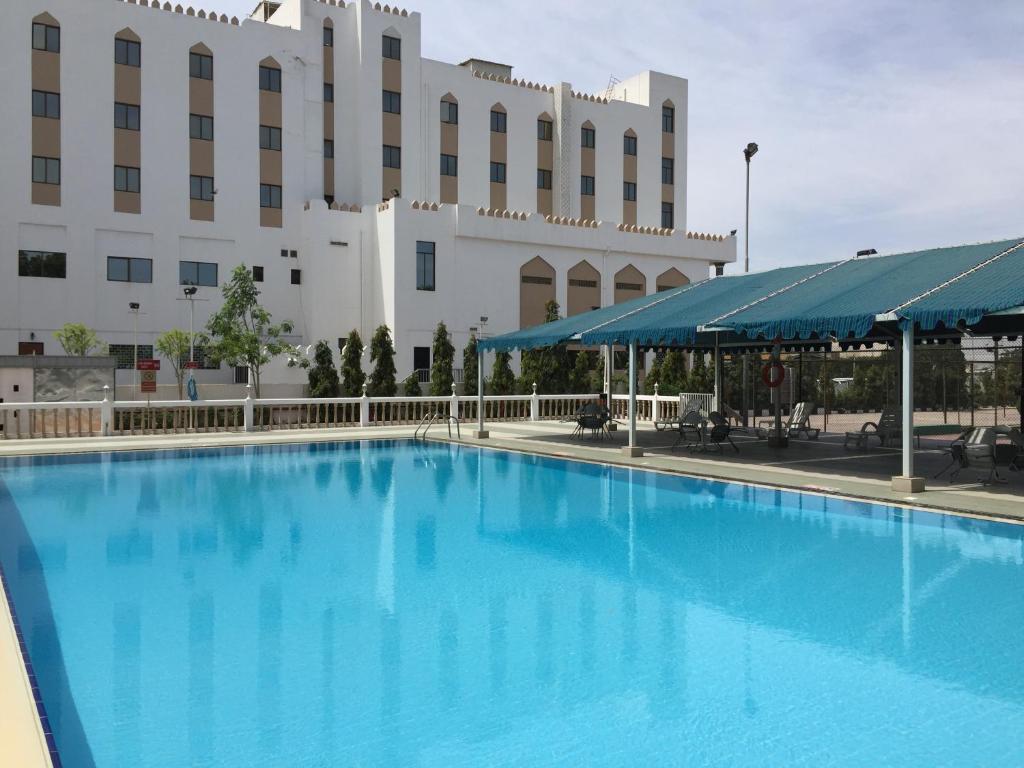 马斯喀特地那假日酒店的酒店前方的大型蓝色游泳池