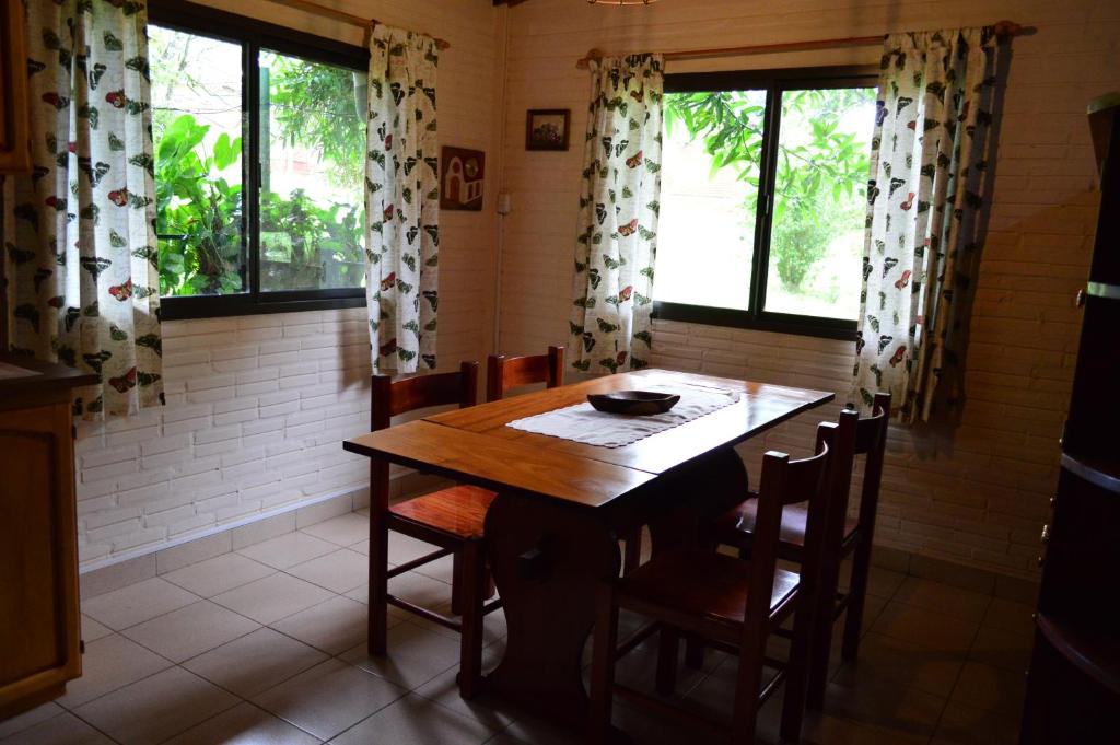 伊瓜苏港Oasis Bed and Breakfast的一间带木桌和一些窗户的用餐室