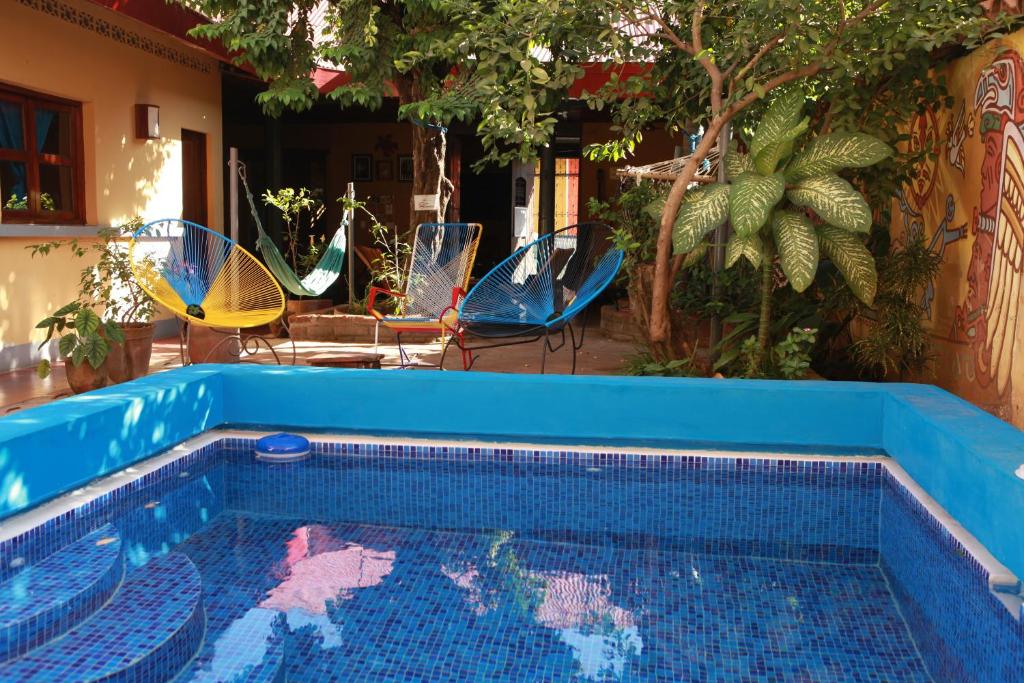 莱昂Hostal La Tortuga Booluda的一个带椅子和遮阳伞的蓝色游泳池
