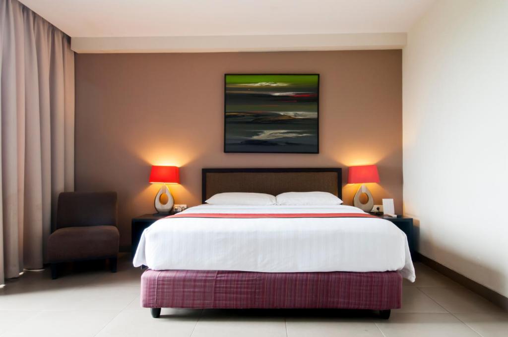库塔100 Sunset Kuta Hotel & Ballroom的一间卧室配有一张大床和一把椅子
