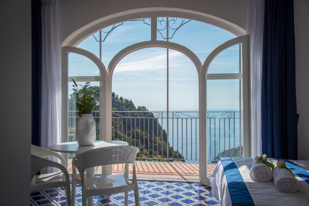 斯卡拉Palazzo San Giovanni Amalfi Coast的卧室设有大窗户和桌椅