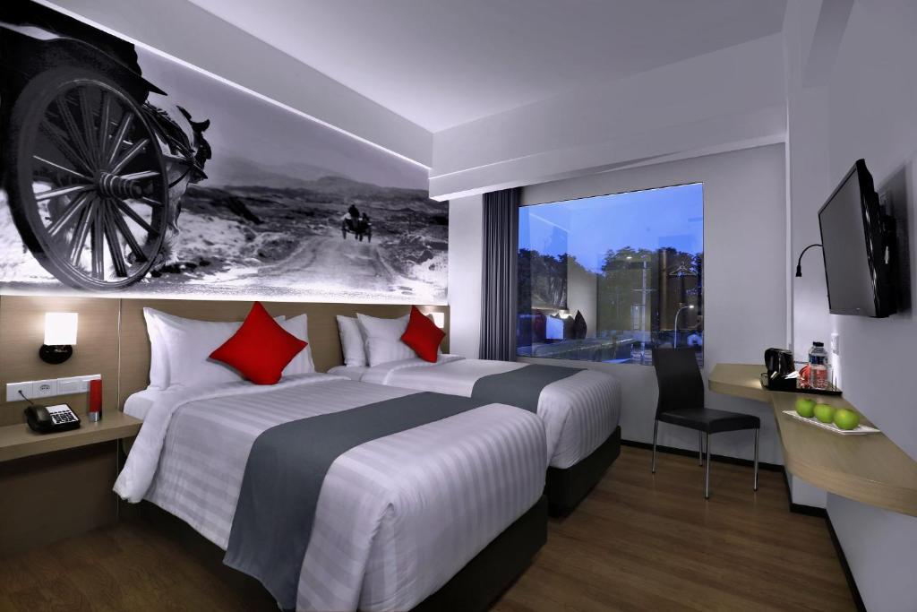 诗都阿佐NEO+Waru-Sidoarjo by ASTON的酒店客房设有一张大床,墙上有轮子
