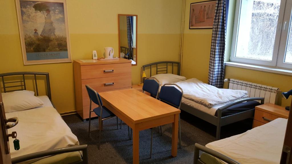 波兹南Hostel Poznań Petit的一间设有两张床和一张桌子及椅子的房间