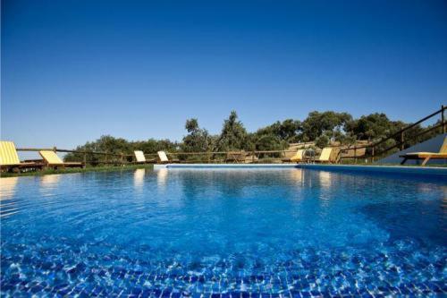 埃武拉奎因塔多斯巴斯托斯酒店的一座蓝色海水和椅子的大型游泳池