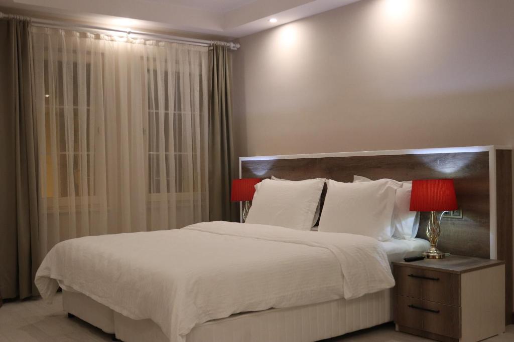 ÇekirgeYankı Hotel的一间卧室配有一张带白色床单和红色灯的大床